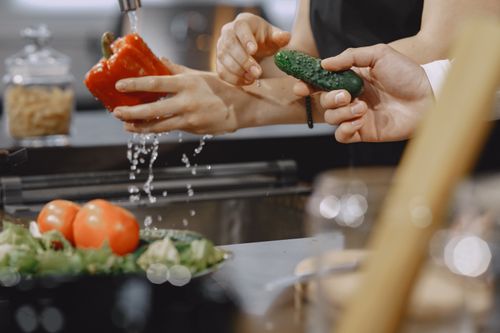 Free Close-up of hands washing vegetables in a modern kitchen sink. Stock Photo