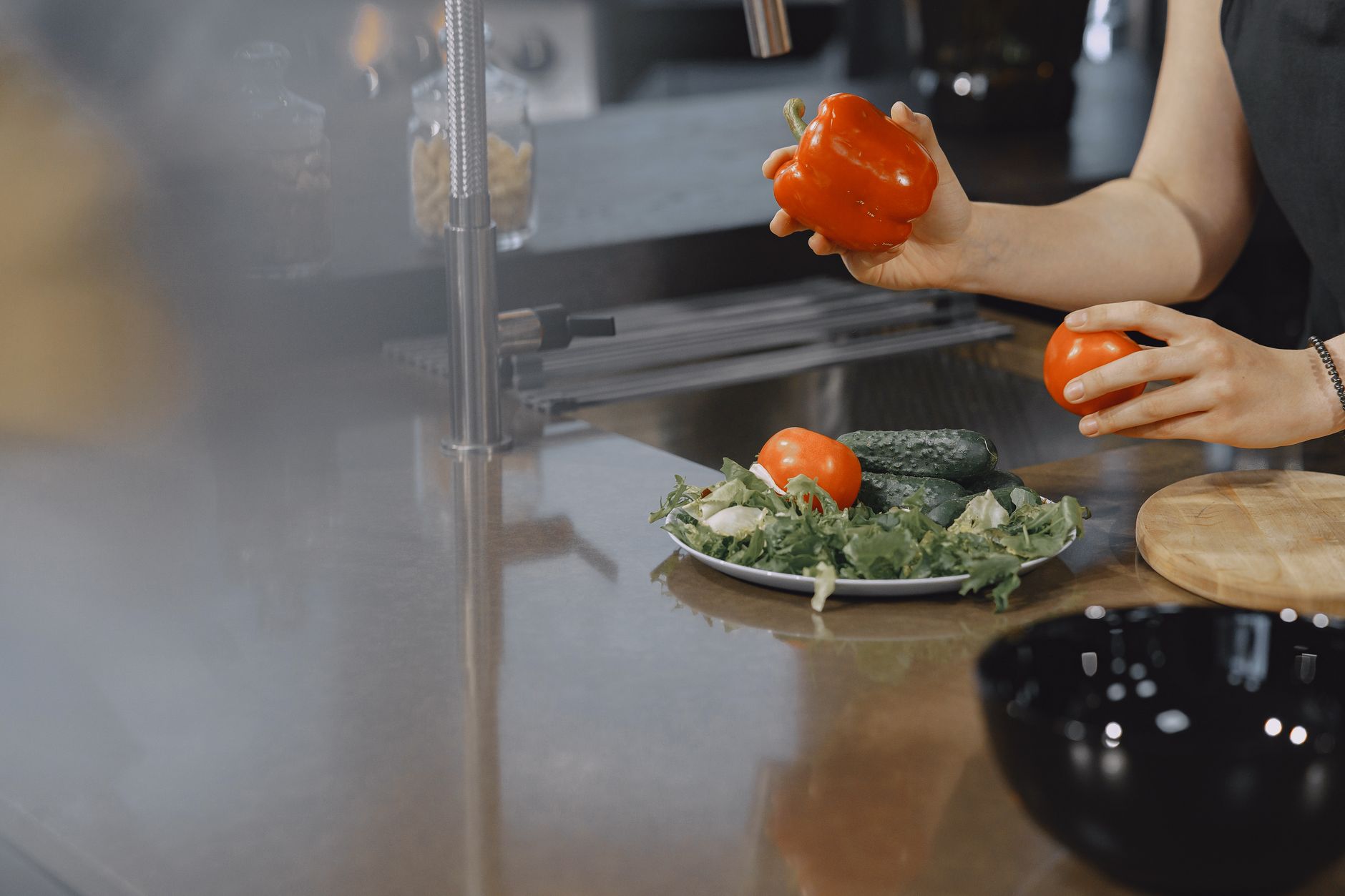 A person preparing fresh vegetables in a modern kitchen setting.