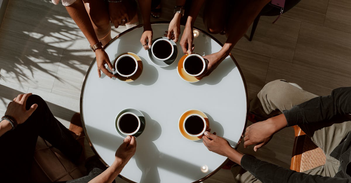 A group of friends enjoying coffee around a café table in a warm setting.