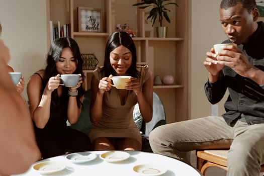 Group of friends laughing and bonding over hot drinks in a welcoming café interior.