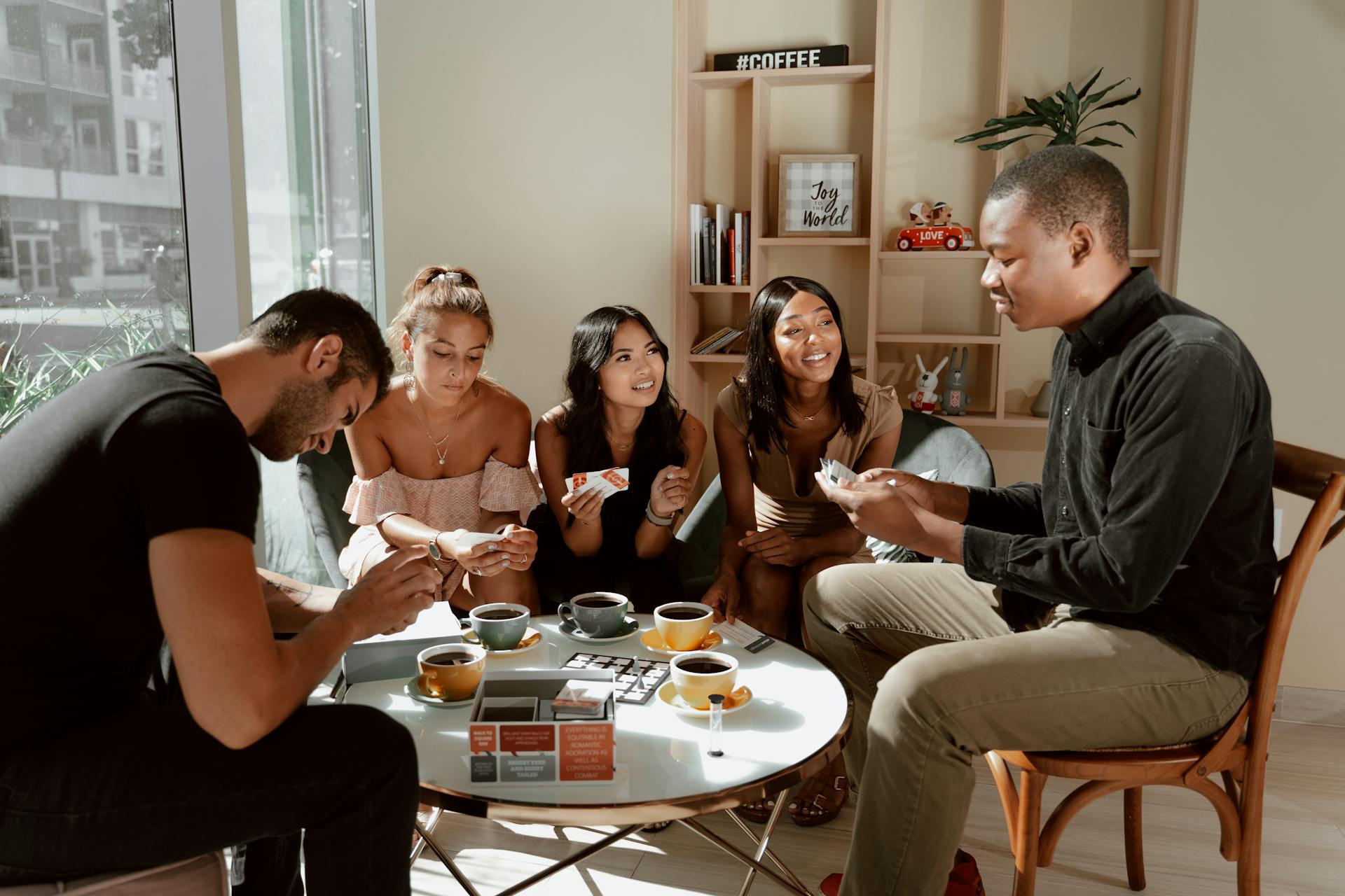 Group of diverse friends playing board games in a cozy café setting, enjoying coffee together.