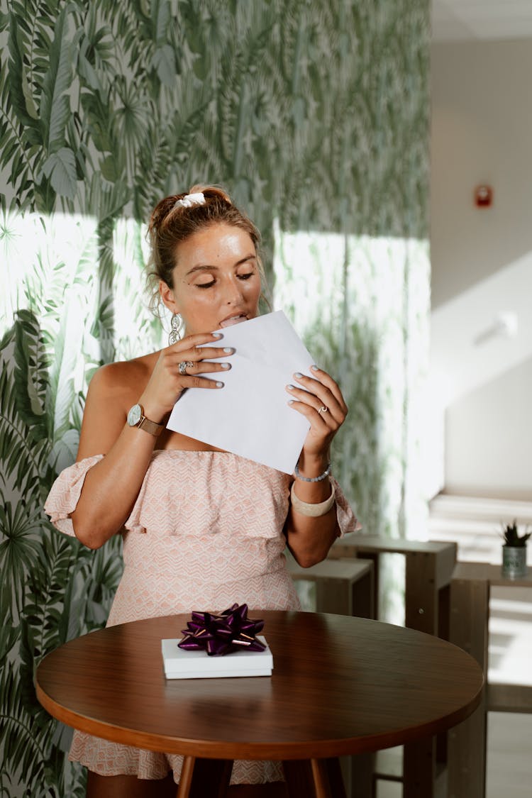 Woman In Pink Dress Sealing An Envelope 