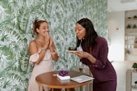 两名妇女在室内庆祝生日，她们手拿蛋糕和礼物，充满了欢乐与幸福