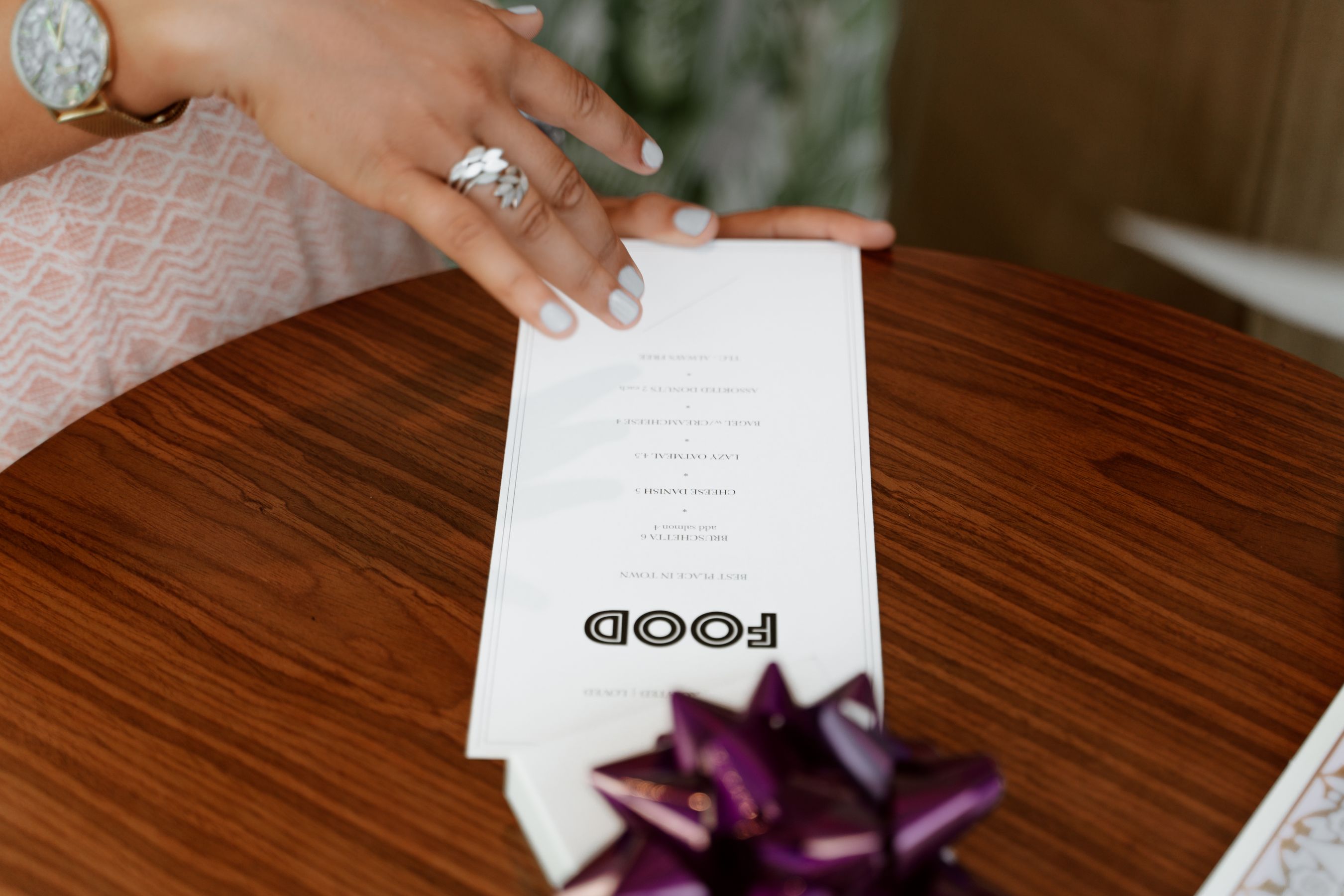 A hand holding a restaurant menu at a wooden table