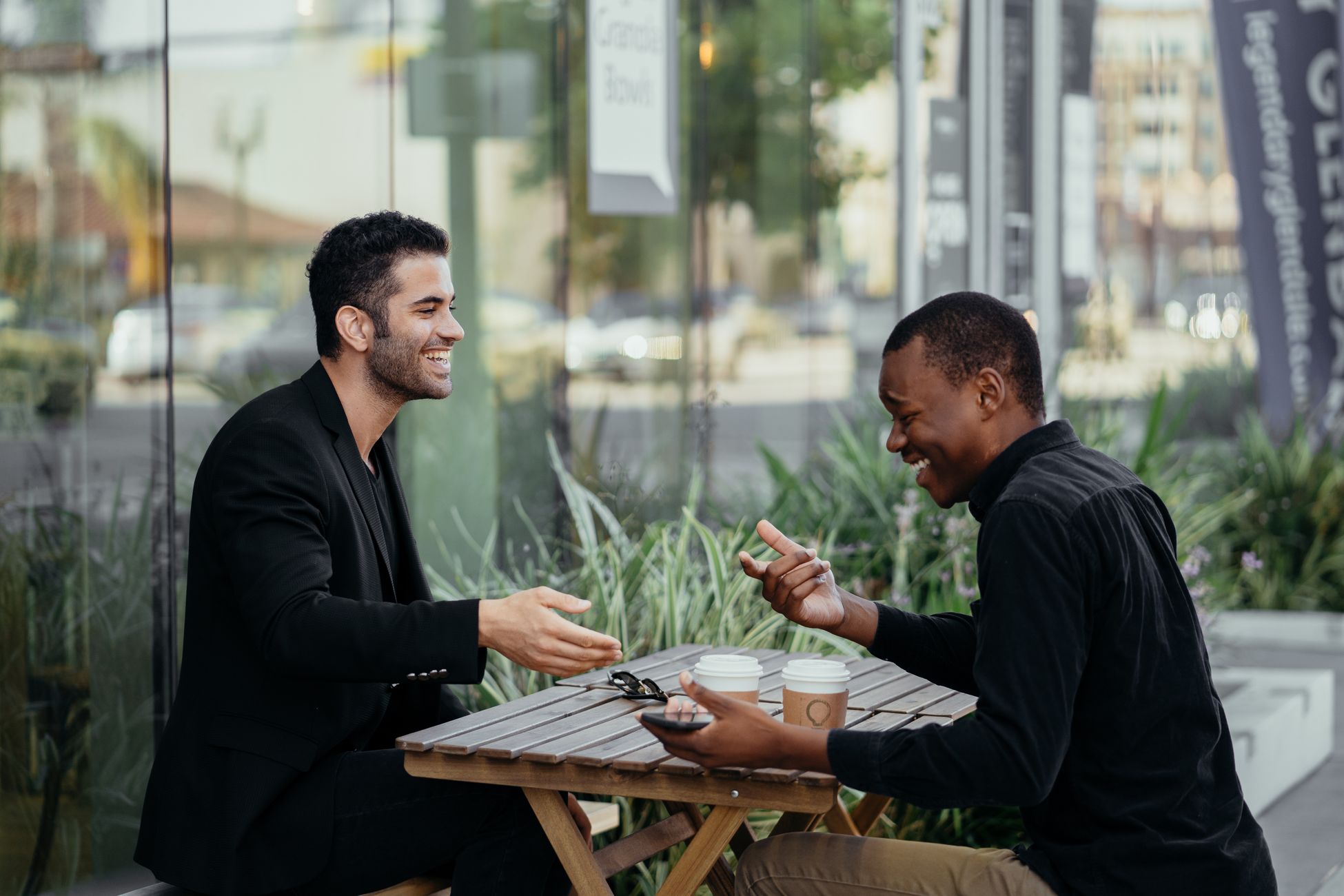 Two friends enjoy a lively conversation over coffee at an outdoor café.