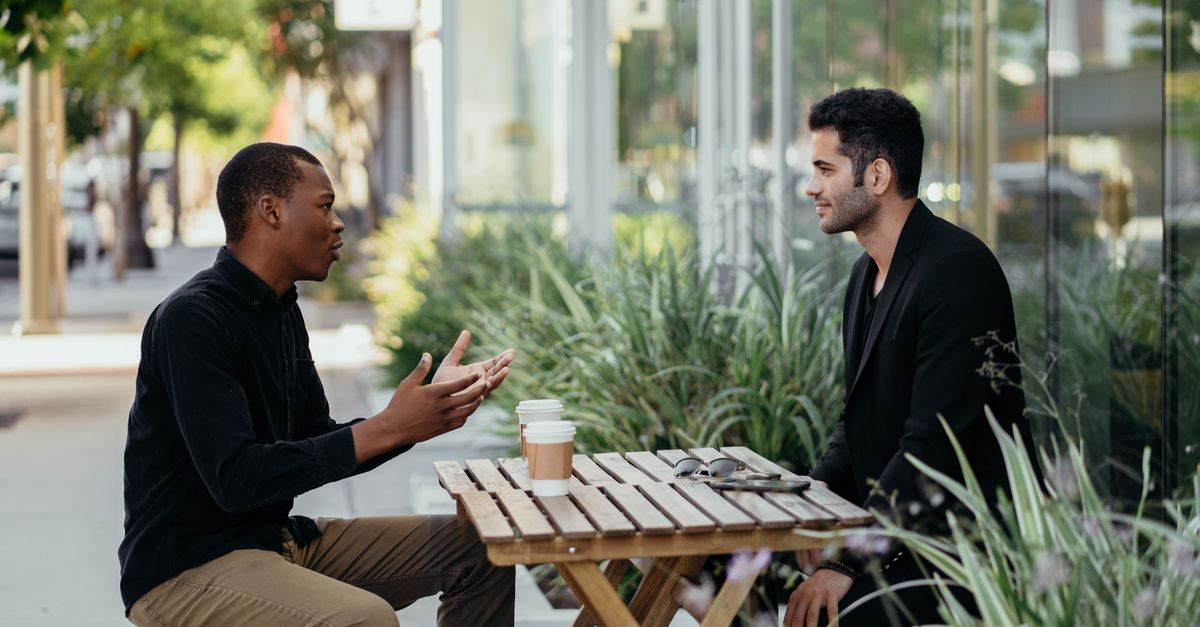 Two men having a business meeting at an outdoor café setting.