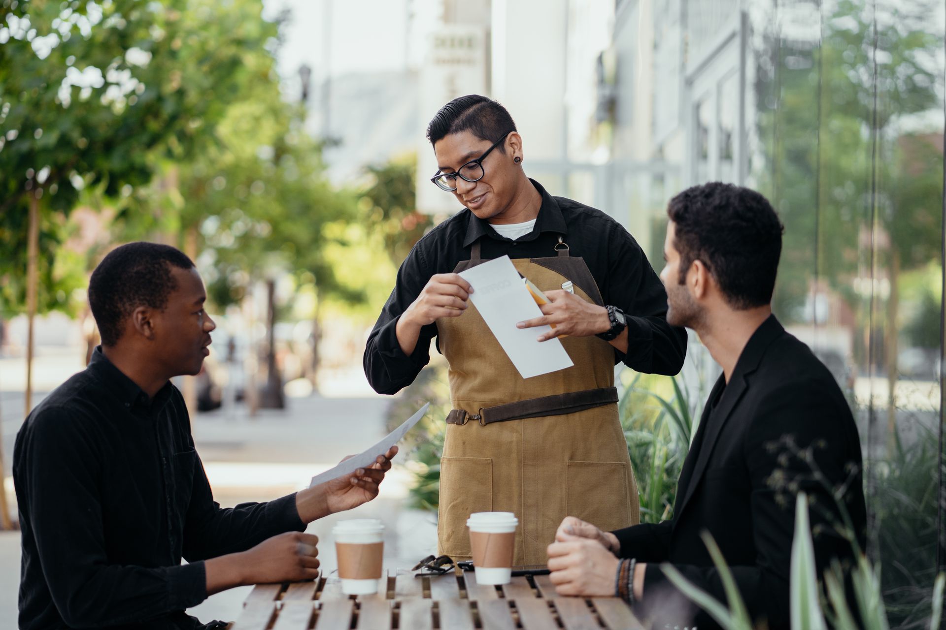 Casual outdoor meeting at a café with diverse friends and friendly waiter.