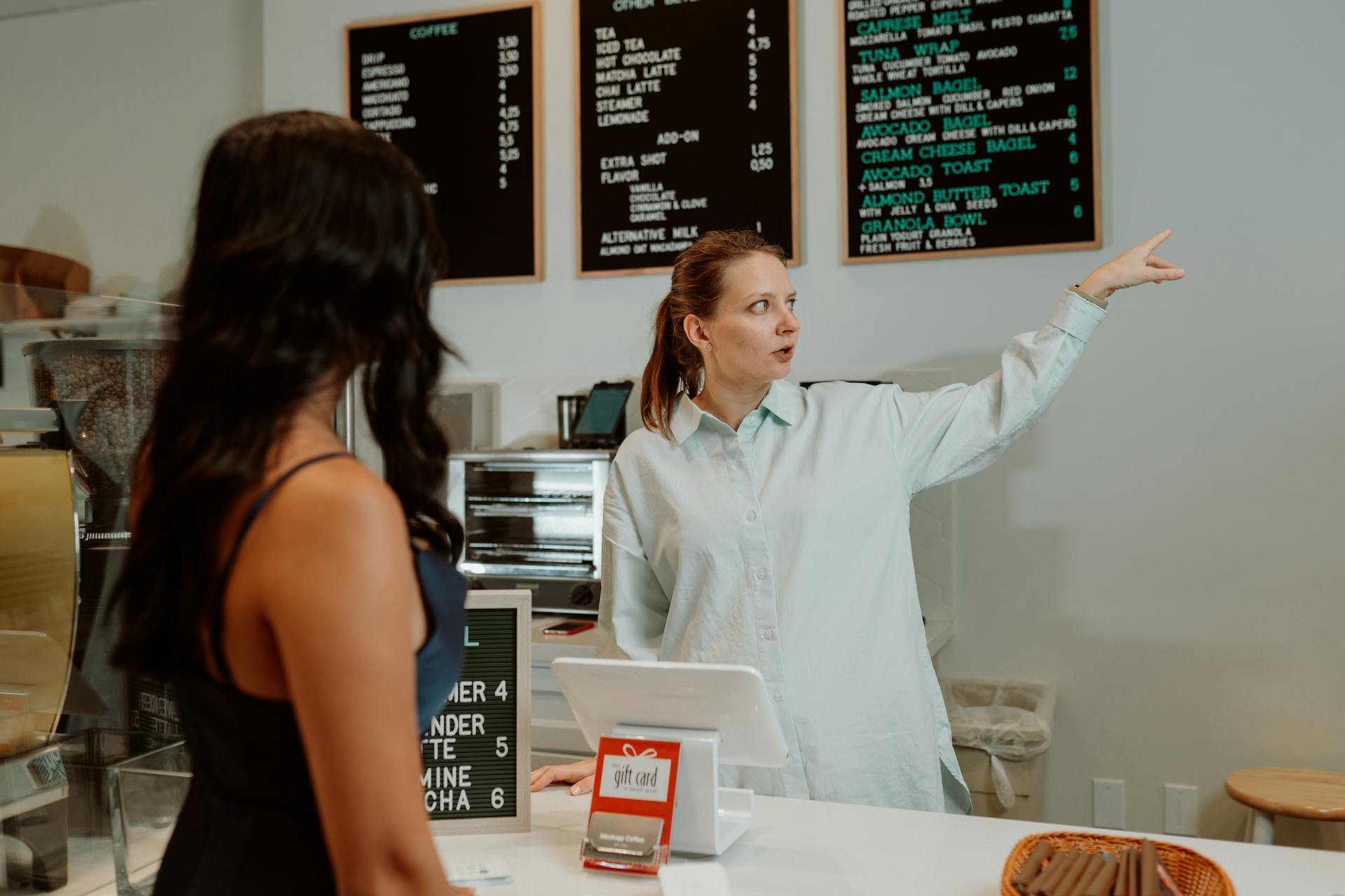 A barista attentively assists a customer at a modern café, showcasing a professional service setting.