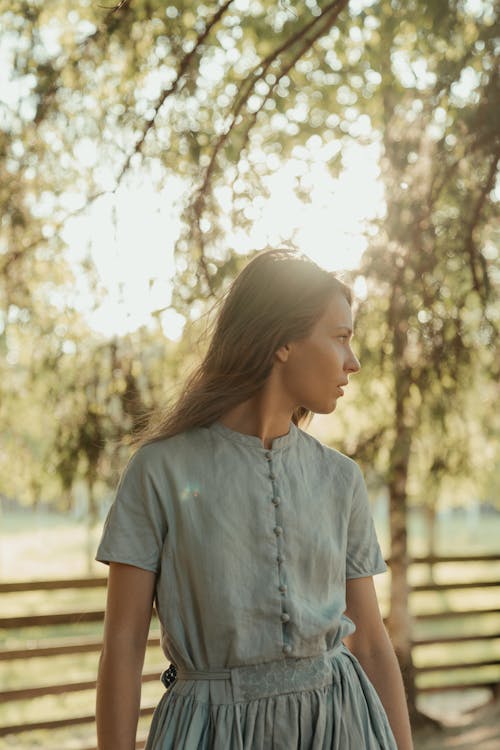Woman in Blue Button Up Shirt Standing Near Trees