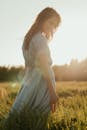 穿着连衣裙的女人在阳光明媚的田野里享受宁静的夏夜，捕捉宁静和大自然的美丽