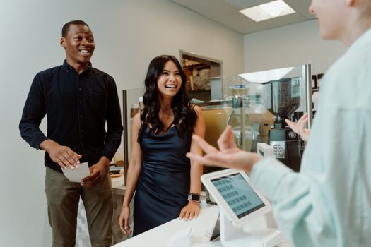 Smiling group at a coffee shop counter, engaging with a cashier, creating a warm atmosphere.