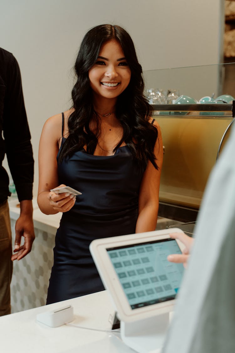 A Woman In Black Dress Paying Bills Through Credit Card