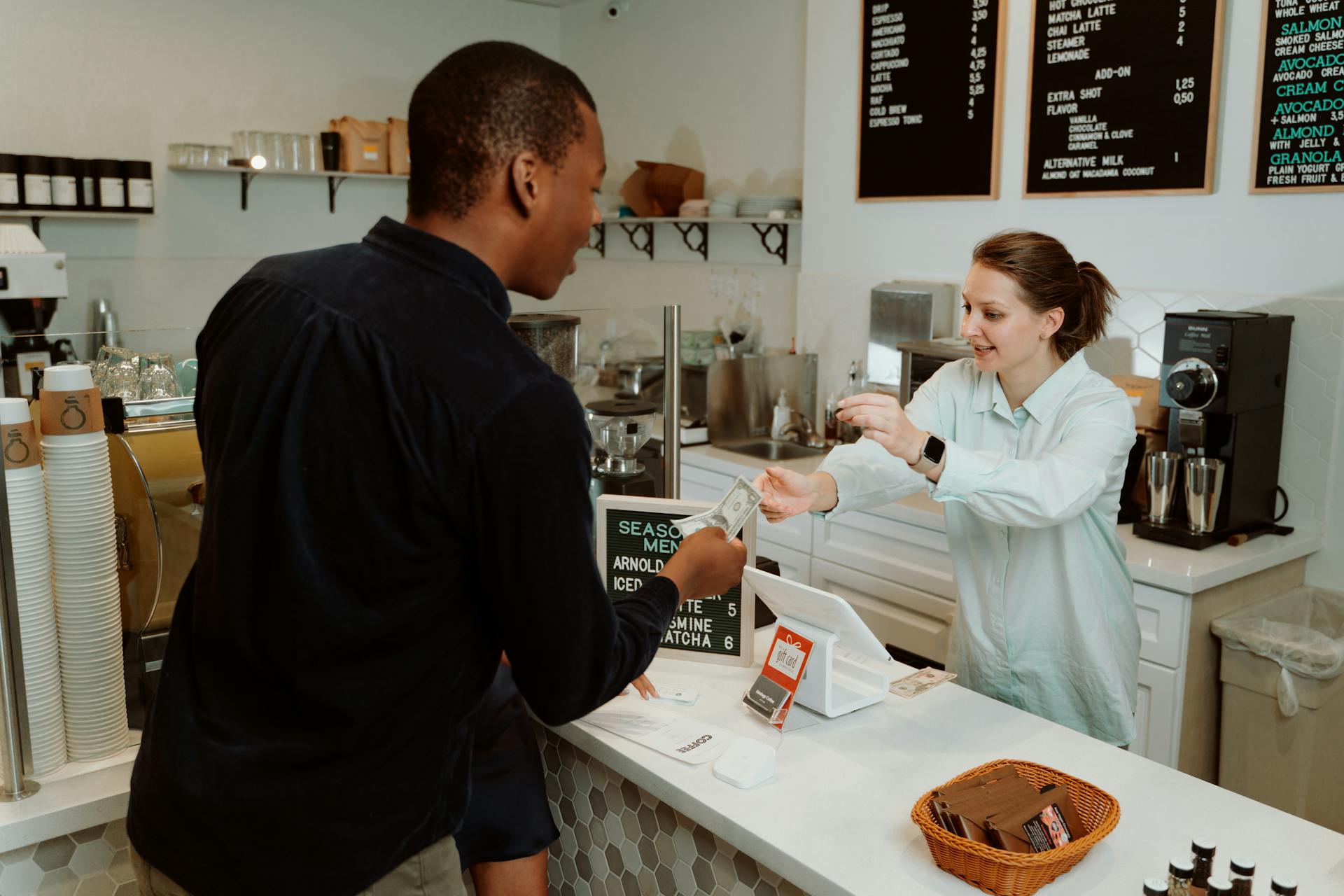 A customer pays for coffee at a café counter, transaction with barista.