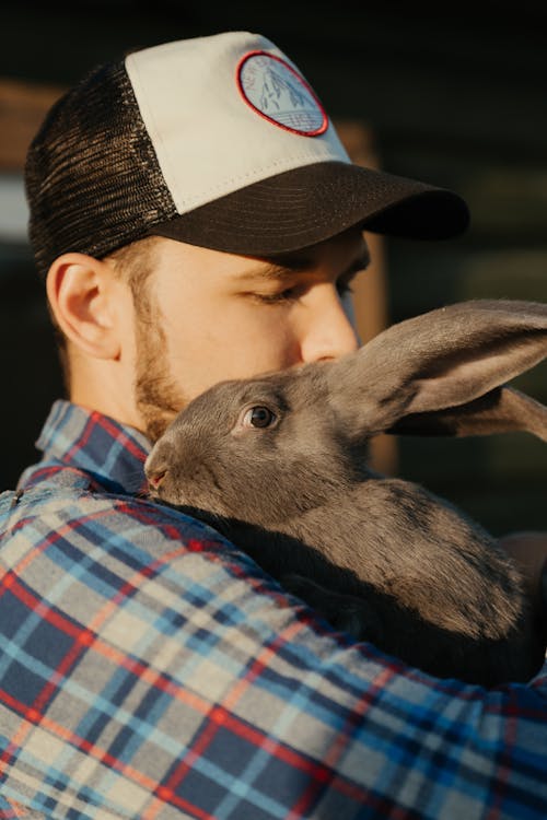 Man in Blue White and Black Plaid Shirt Holding Gray Rabbit