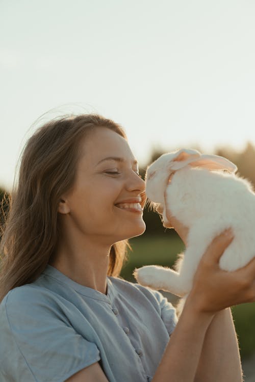 Free Woman in Blue Crew Neck Shirt Holding White Puppy Stock Photo