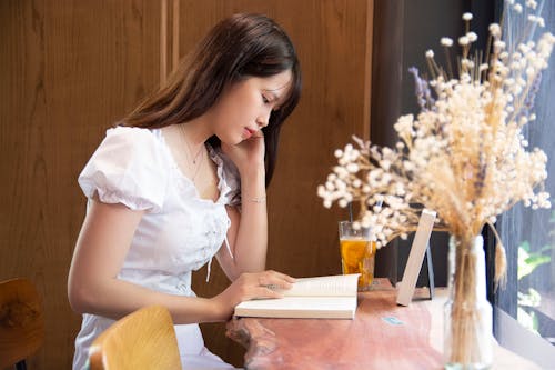 A Woman Wearing a White Blouse Reading a Book