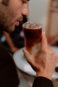 A man enjoying a refreshing iced coffee, highlighting its rich texture.