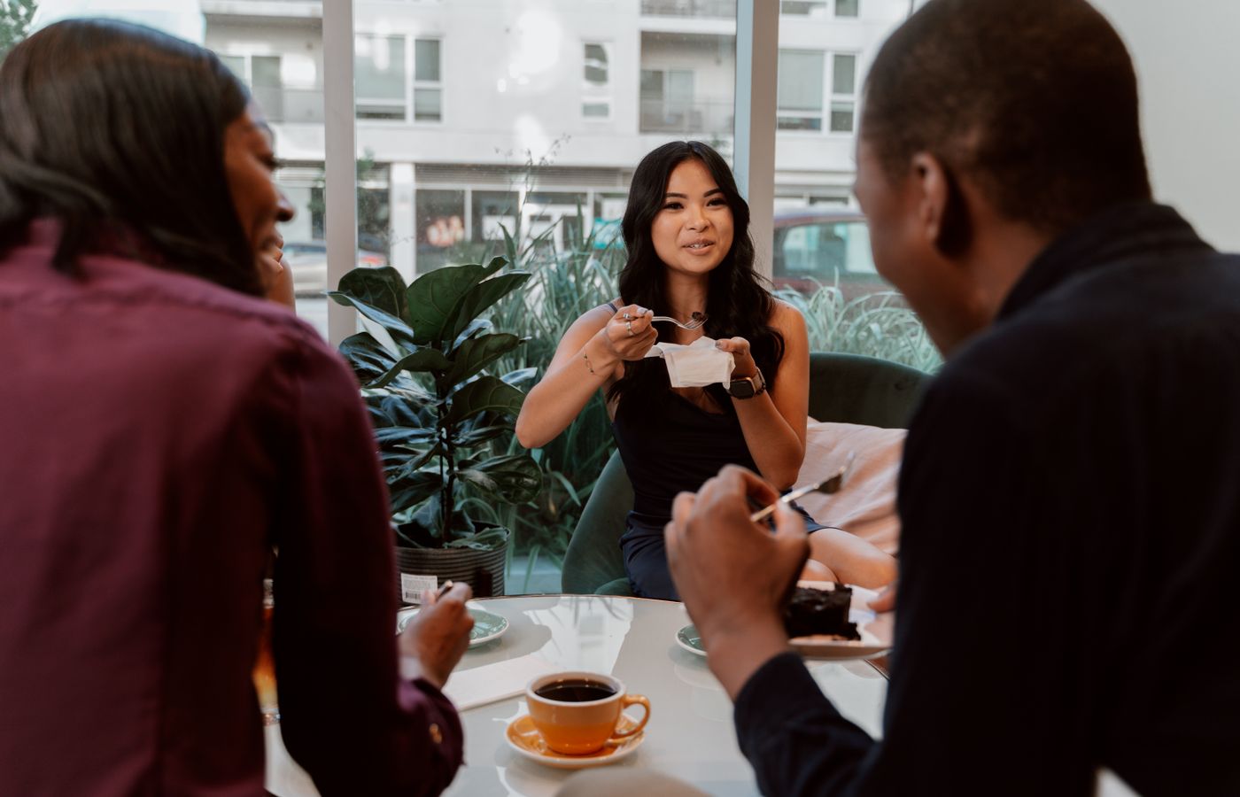 Diverse group of friends enjoying coffee and cake in a modern café. Perfect for lifestyle and social themes.