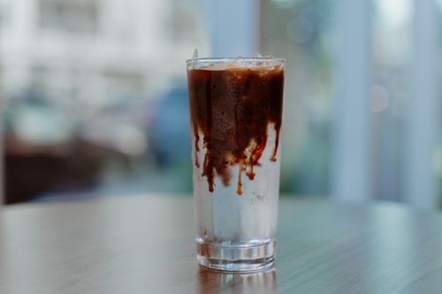 Free Refreshing glass of iced coffee with a creamy swirl on a wooden table indoors. Stock Photo