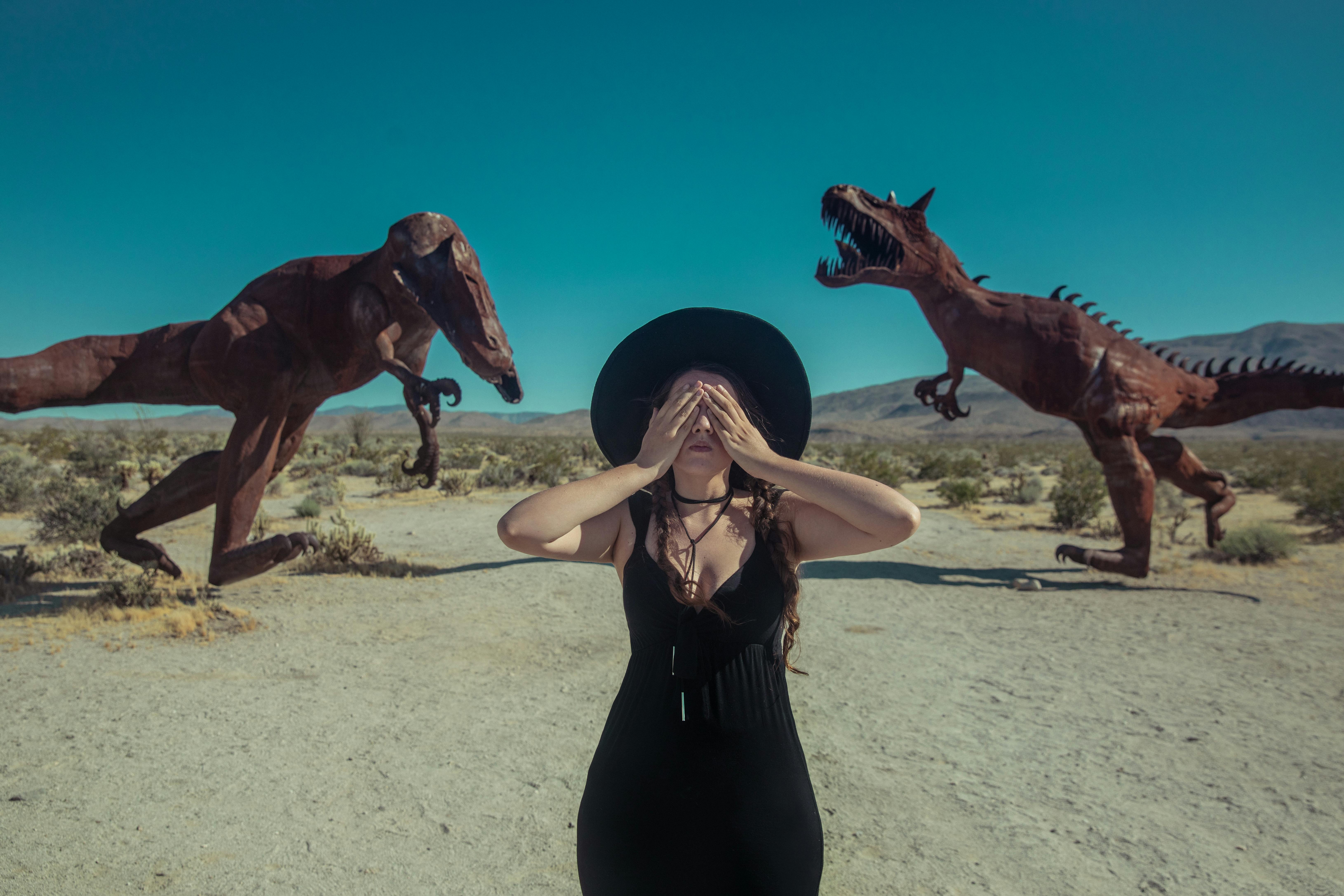 a woman covering her eyes near the dinosaur sculptures in borrego springs california