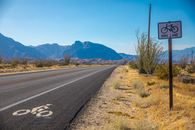 长长的沙漠道路上有自行车道标记和标志，远处是山脉