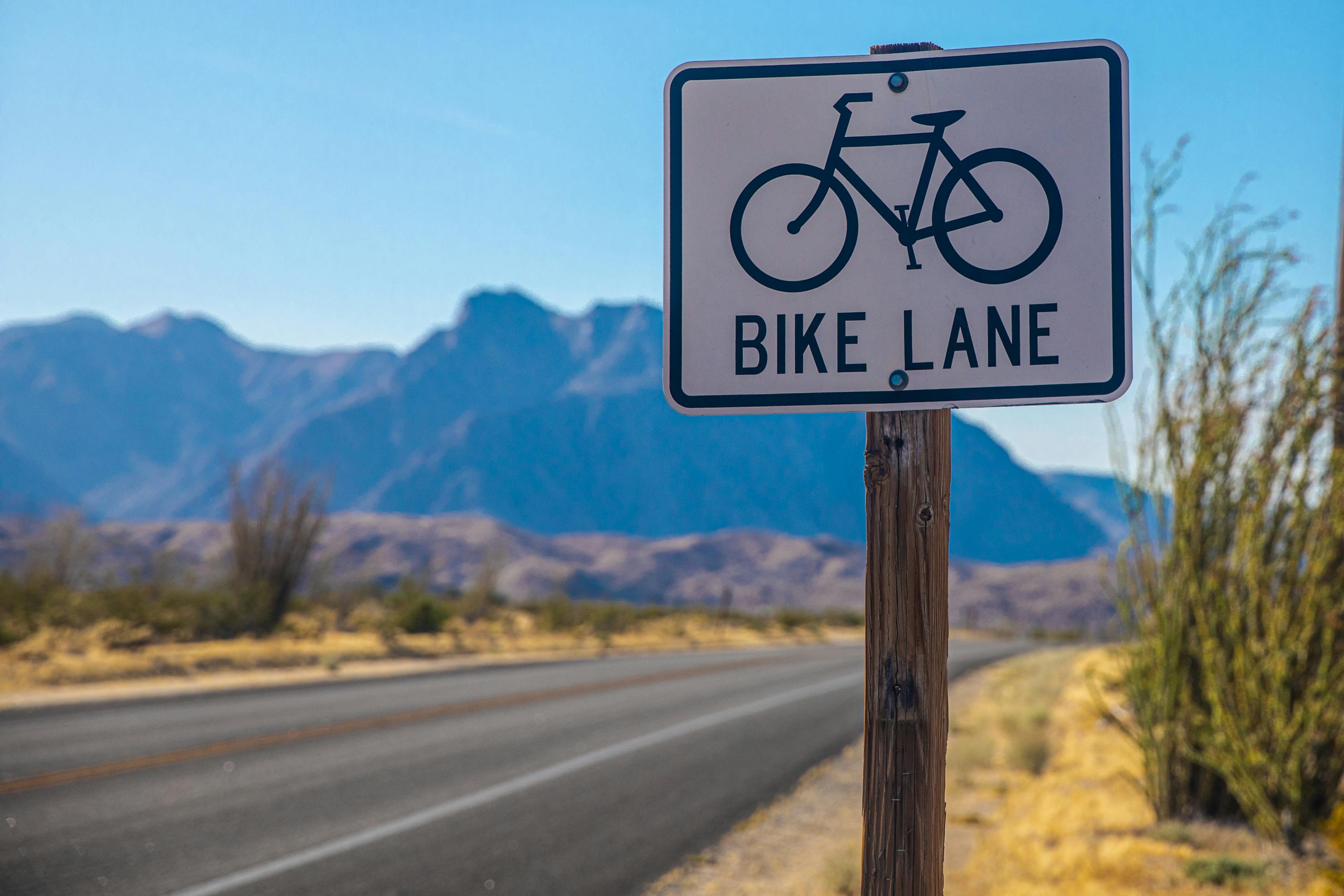 a black and white bike lane sign on a wooden pole