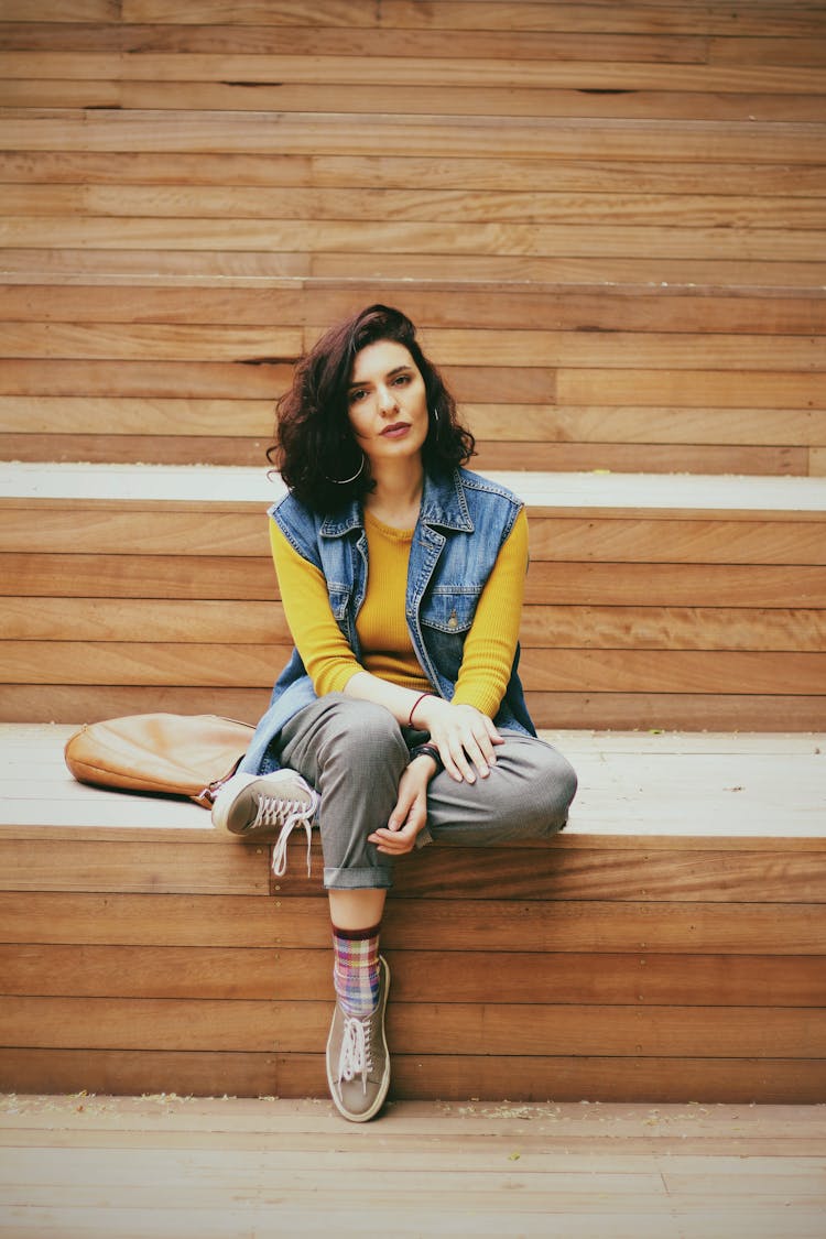 Beautiful Woman In Blue Denim Jacket Sitting On Wooden Bleachers