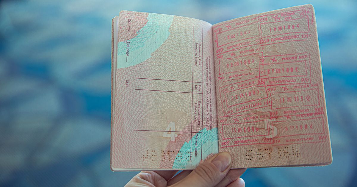 UK Skilled Worker Visa Requirements: Complete 2026 Guide — Close-up view of an open passport displaying various travel stamps in an airport setting.