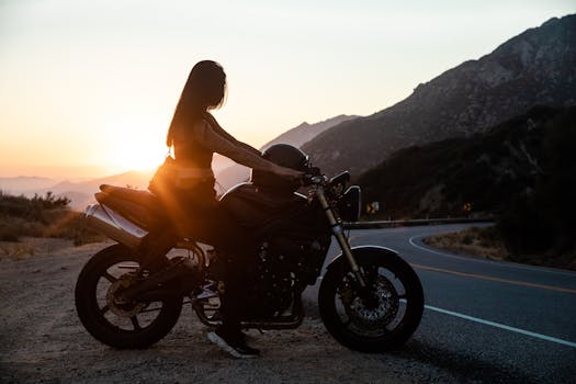 Woman on a motorcycle at sunset on a scenic mountain road.