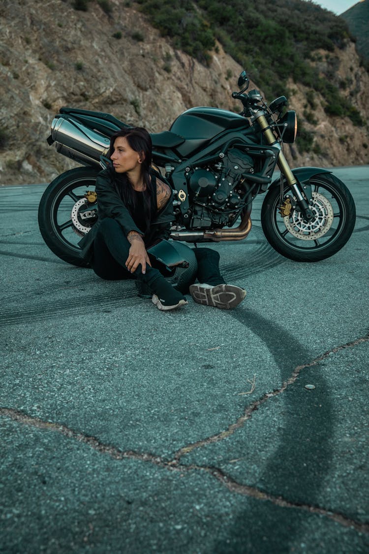 Woman Sitting Beside Her Motorcycle On Roadside