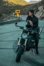 A Person in a Black Jacket Riding a Black Motorcycle on the Road