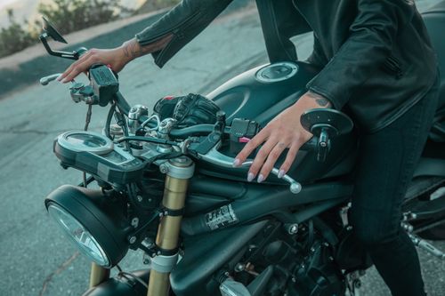 Free A person wearing a black leather jacket holds the handlebars of a motorcycle, highlighting the ride's sleek design. Stock Photo