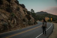 Woman in Black Jacket Walking on the Road