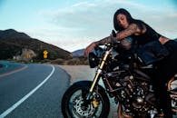 一名纹身女子骑着摩托车，在蜿蜒的道路旁，于宁静的风景中捕捉到了自由的本质