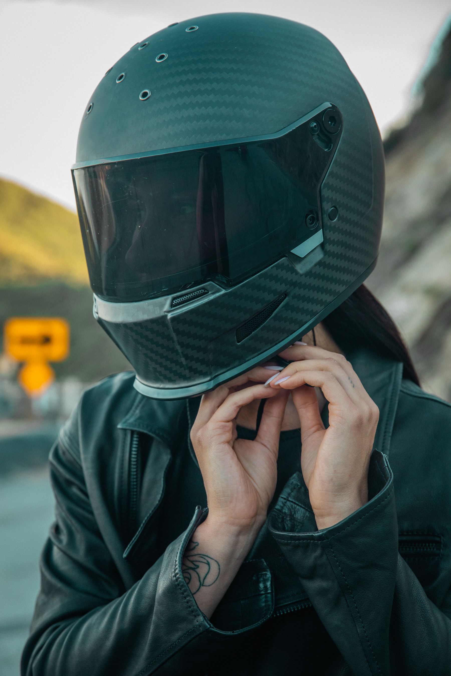 Motorcycle rider wearing a carbon style full face helmet and black leather riding jacket