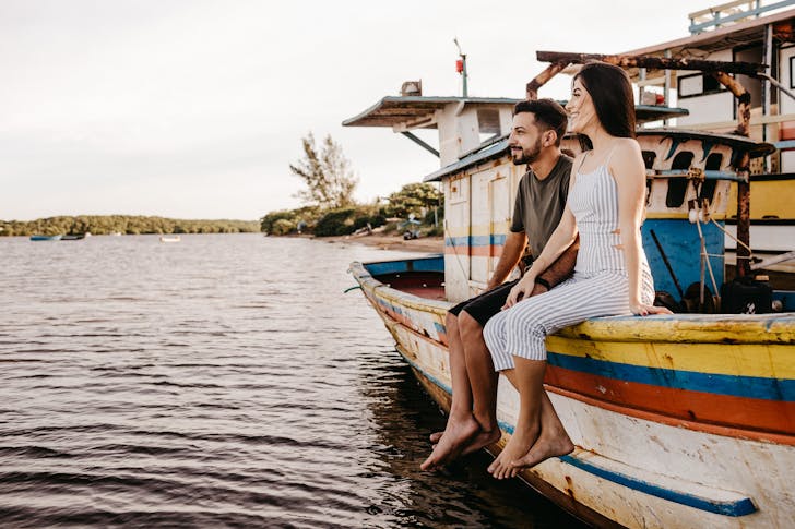 Joyful couple sitting on old boat and holding hands