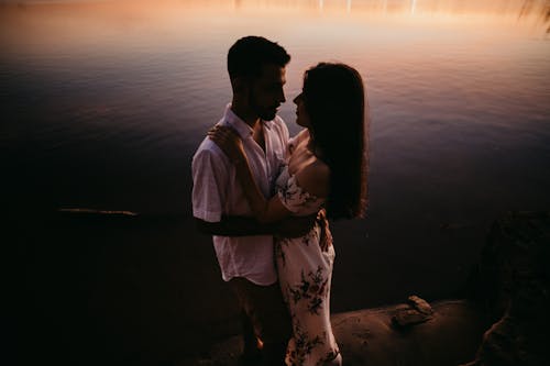 Loving couple bonding on river shore in evening
