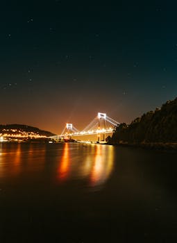 宁静的水域上，一座明亮的桥梁倒映在星空下，构成了令人惊叹的夜间景观