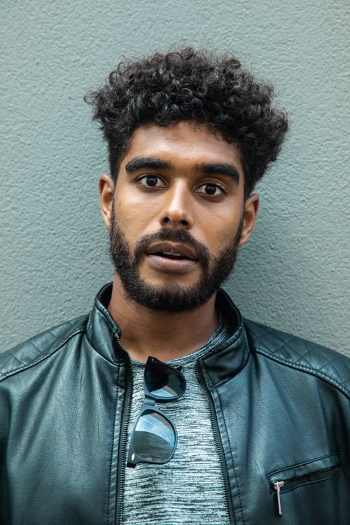 Free Portrait of a stylish man with curly hair and beard in a black leather jacket Stock Photo