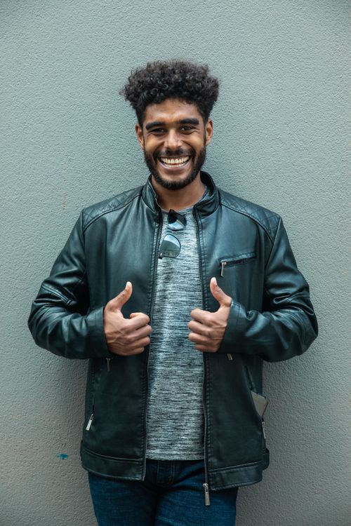 Free Confident young man in a black leather jacket giving thumbs up with a smile. Stock Photo