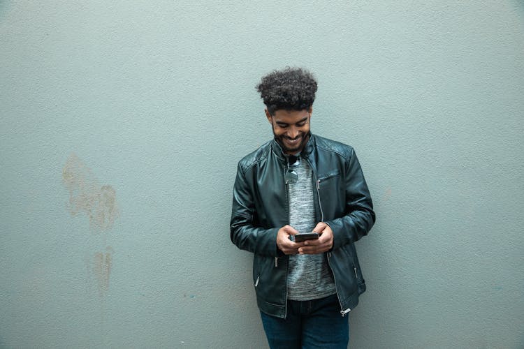 A Man Smiling While Texting 