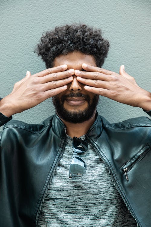 Man Wearing a Leather Jacket Covering His Eyes