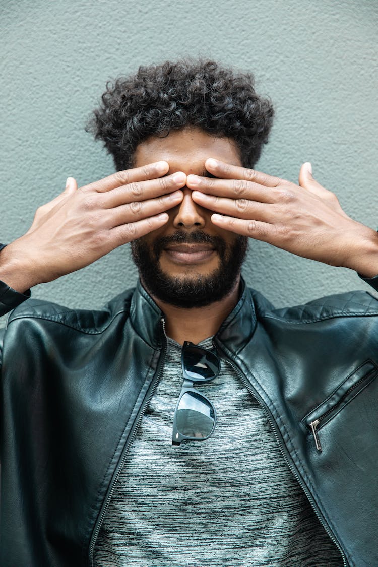 Man Wearing A Leather Jacket Covering His Eyes