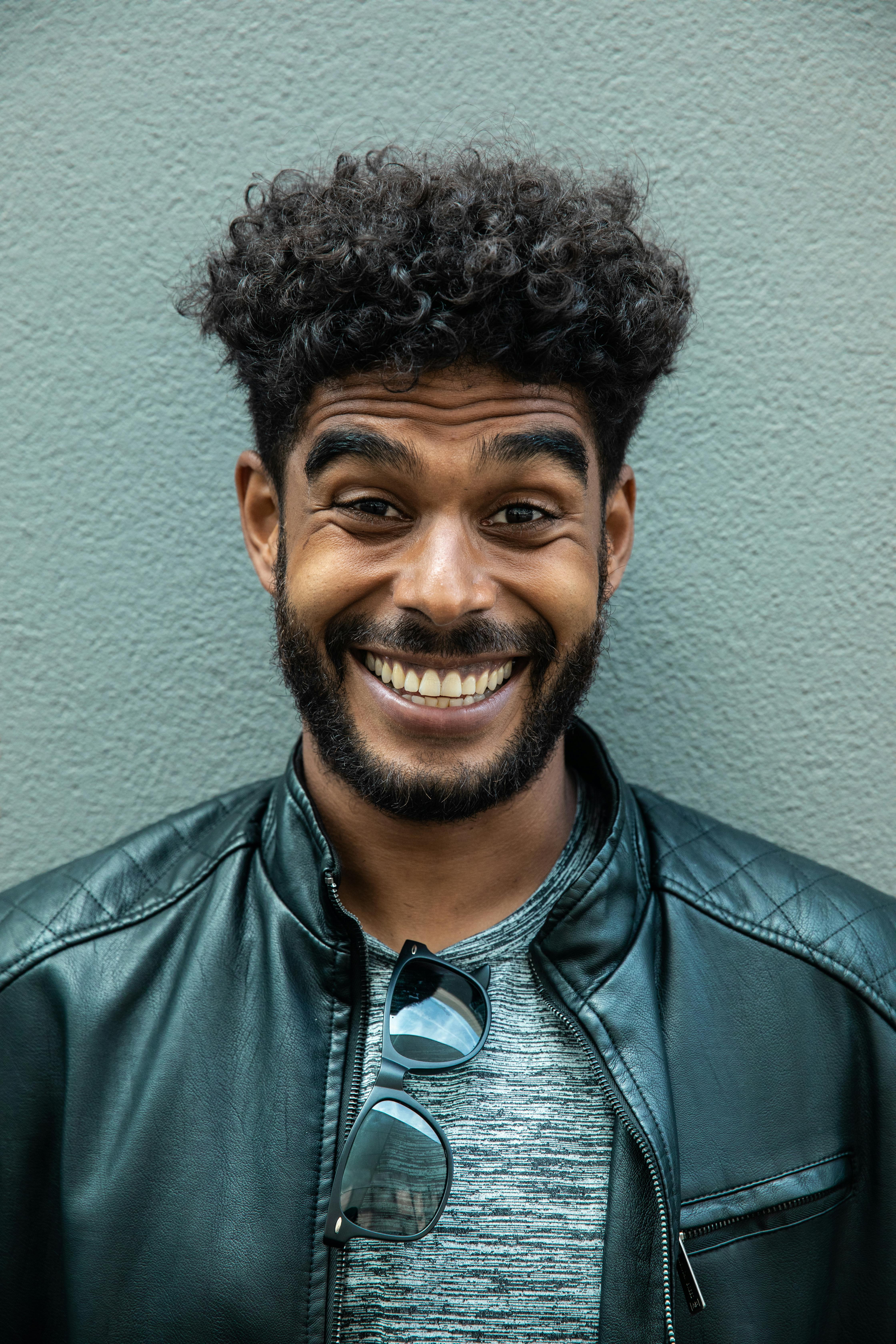 一位充满活力的年轻人，面带富有表现力的微笑，留着卷发