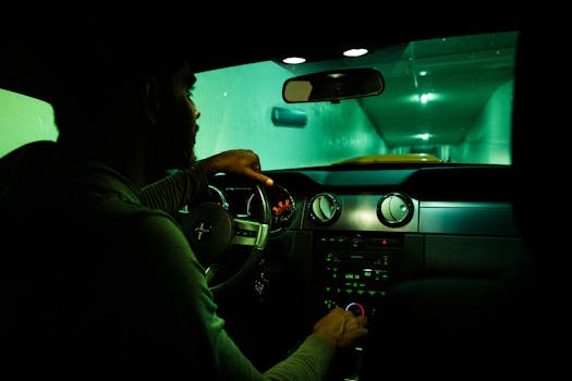 A silhouette of a man driving through a dimly lit tunnel at night.