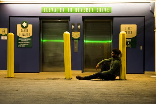 Man Sitting on Ground Near an Elevator Lobby