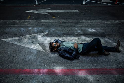 Homem De Jaqueta Cinza Deitado No Chão De Concreto Cinza