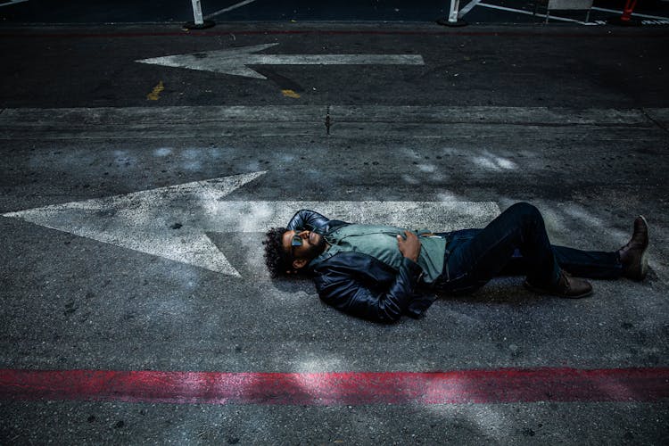 Man Wearing Jacket Laying On Concrete Road