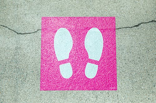 White and Pink Foot Print Signage on Concrete Surface