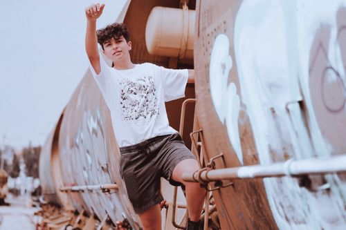 Free Young boy climbing a graffitied train, capturing adventure and youthful exploration in an urban setting. Stock Photo